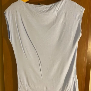 Ljusblå ärmlös topp Livia S - Säljer en ljusblå ärmlös topp från Livia i storlek S. Toppen har en enkel och clean design med rund halsringning och mjukt, tunt material som känns skönt mot huden. Perfekt för dig som gillar minimalistisk stil och vill ha något lätt och luftigt.