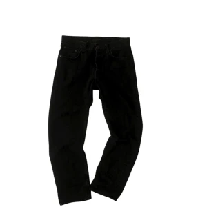 Svarta jeans från Nudie Jeans - Svarta jeans från Nudie Jeans med klassisk femficksdesign och diskret broderad bakficka. Jeansen har rak passform och är tillverkade i slitstarkt bomullstyg. Perfekta för dig som gillar en clean och stilren look