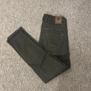 Replay svarta jeansbyxor  - Svarta jeansbyxor från Replay i modellen anbass Klassisk femficksdesign, med Replay-logga på bakfickan och läderpatch i midjan. Jeansen är i stretchigt material för en bekväm passform och har smala ben hela vägen ner. Fråga vid fundering