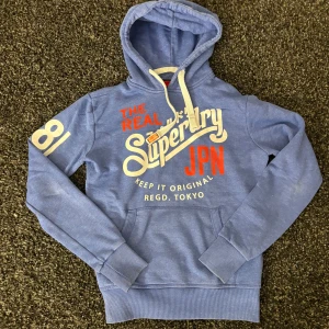 Superdry hoodie (sällsynt) - Säljer nu denna eftertraktade hoodie ifrån Superdry. Skick 8/10. Sjukt snygg och passar perfekt nu till hösten! Obs kan gå ner i pris vid snabb och smiddig affär!