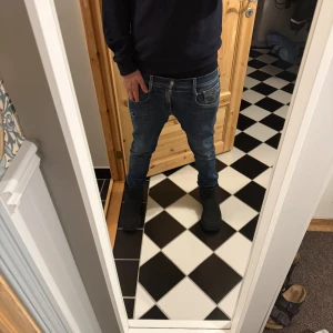 Svarta UGG boots i mocka - Säljer ett par klassiska svarta UGG boots i mjuk mocka med rund tå och platt sula. Skorna har en enkel och stilren design som passar perfekt till jeans eller leggings. Insidan är fodrad för extra värme och komfort under kalla dagar.