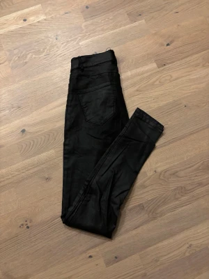 Svarta skinny jeans från Vero Moda - Snygga svarta jeans från Vero Moda med skinny fit och hög midja. De är tillverkade i ett stretchigt bomullsmaterial som sitter tajt och bekvämt. Klassisk femficksdesign och stilren look som funkar till allt. Perfekta för dig som gillar en smal siluett.