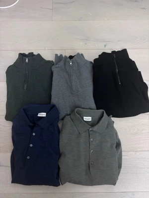 Half zip och pikétröjor från John Henric - Fem stilrena tröjor från John Henric: tre half zip-tröjor i mörkgrön, grå och svart samt två pikétröjor i marinblå och grågrön. Alla har klassisk design med diskreta detaljer och mjukt material som passar perfekt till jeans eller chinos.