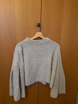 Ljusblå stickad tröja från Mango - Säljer en ljusblå stickad tröja från Mango i storlek S. Tröjan har loose passform, croppad längd och långa, voluminösa ärmar med ribbad struktur. Perfekt för dig som gillar en chill och trendig look.