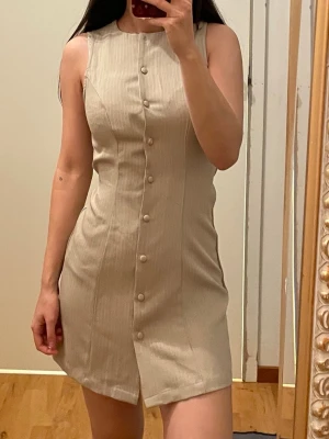 Beige kort klänning (SHEIN) - Snygg beige kort klänning, ärmlös modell med figurnära passform och rund halsringning. Helt ny och oanvänd, säljer för den är för kort enligt mig ;)