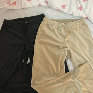 Mjukisbyxor från Gina Tricot i svart & beige - Två par mjukisbyxor från Gina Tricot i storlek S. Ena paret är helsvart och det andra är beige, båda med bred resår i midjan och snörning framtill. Materialet är mjukt och lite glansigt, perfekta för chill dagar hemma eller när du vill vara extra comfy. Paketpris 250 skriv om du bara vill ha ett par😚