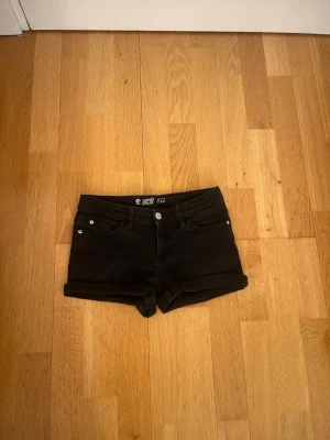 Svarta jeansshorts från Cubus - Svarta jeansshorts från Cubus med klassisk femficksdesign, uppvikta benslut och justerbar midja på insidan. Snygg och enkel modell som passar perfekt till sommaren. 