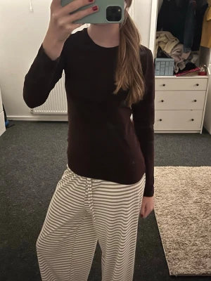 Mörkbrun långärmad bomullströja - Säljer en enkel och stilren mörkbrun långärmad tröja i mjuk bomull. Tröjan har rund hals och en normal passform som sitter snyggt på kroppen. Perfekt att matcha med jeans eller mjukisbyxor för en chill look. Använt fåtal gånger, inget fel på den🫰