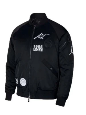 Svart bomberjacka Air Jordan - Svart bomberjacka från Air Jordan med vita tryck och patchar både fram och bak. Jackan har dragkedja, ribbade muddar och flera coola detaljer som logotyp, årtal och text. Materialet är blankt och känns sportigt, perfekt för dig som gillar streetwear.