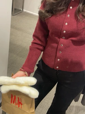 Vinröd kofta med knappar - Säljer en vinröd kofta med silvriga knappar framtill. Koftan har långärmad design och är stickad i ett mjukt material som passar perfekt för kyligare dagar. Enkel och stilren modell som är lätt att matcha med olika outfits.