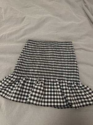 Svartvit rutig volangkjol - Säljer en kort kjol med svartvitt rutigt mönster och volang nedtill. 