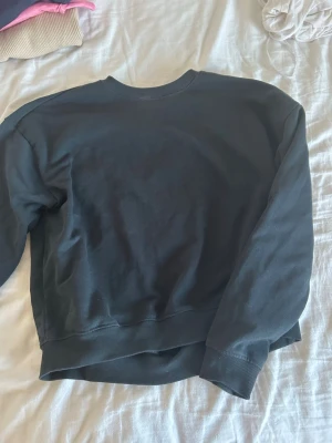 Svart sweatshirt från 157, storlek S - En enkel och stilren svart sweatshirt från 157 i storlek S. Tröjan har rund halsringning, ribbade muddar vid ärmslut och nederkant samt mjuk insida i fleece. Perfekt för chill dagar eller när du vill ha något bekvämt.