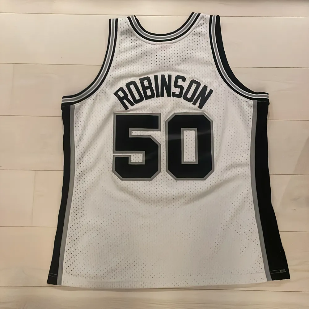 Hej,  Säljer ett San Antonio Spurs basketlinne av märket Mitchell and Ness (Hardwood classic). Linnet är i gott skick utöver två mindre hål vid främre etiketten (se bild 3). . Toppar.