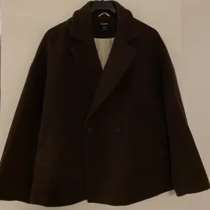 Brun kort kappa i ull från Lindex i storlek xs. Köpt förra året och använd fåtal gånger