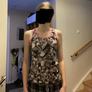 Grått och rosa linne - Ett träningslinne med svart,vitt,grått mönster på framsidan och rosa färg på baksidan från Soc💕Använd ca 7 gånger och har inga fel. Strl. 158/164 men passar som XS☺️