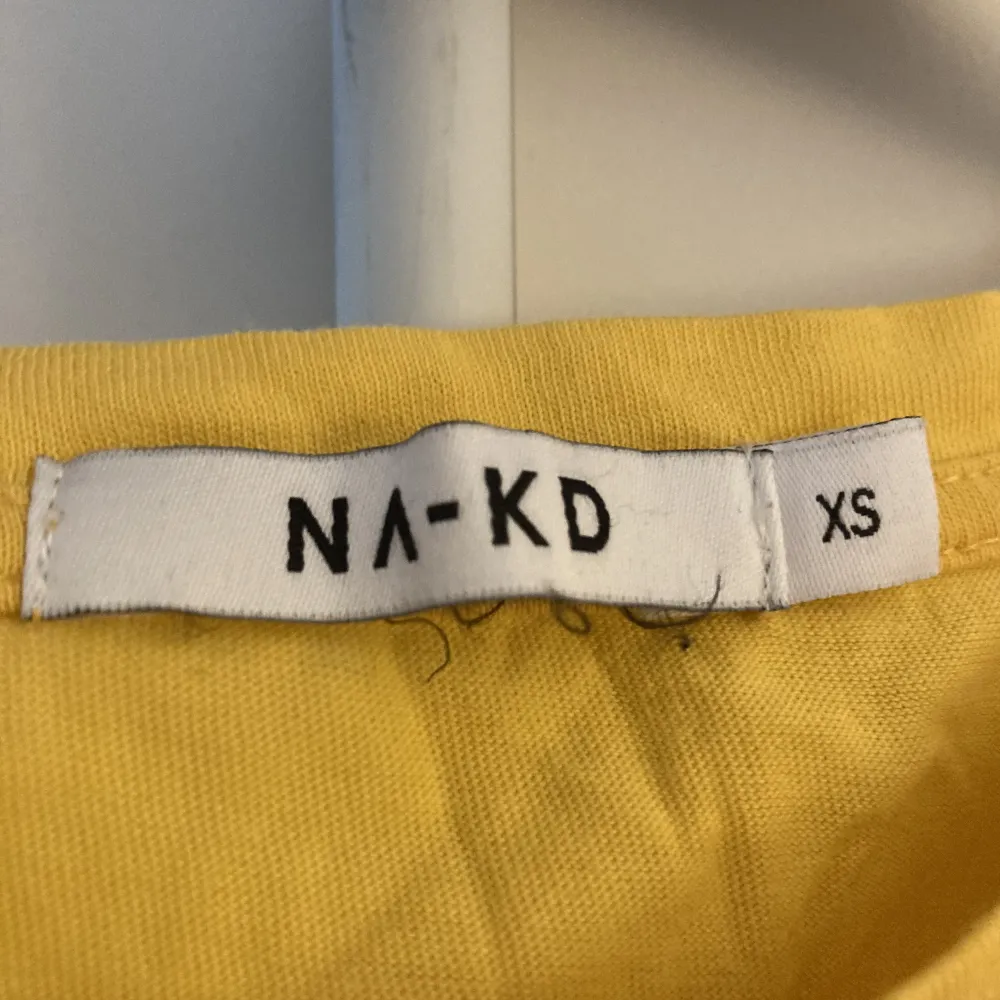 Gul t-shirt från NAKD med svart tryck. Stryks innan den skickas. T-shirts.