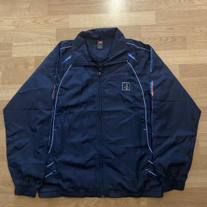 Adidas windbreaker - Mörkblå winbreaker från Adidas i storlek XL, men den är liten i storlek så passar för en med M och även L. Den är helt oanvänd, och är i mycket bra skick.