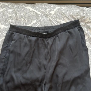 Svarta satin byxor - Svarta satin byxor med vida ben, sitter otroligt bra upptill och super sköna. Jag är 172cm och de går hela vägen ner på mig. 