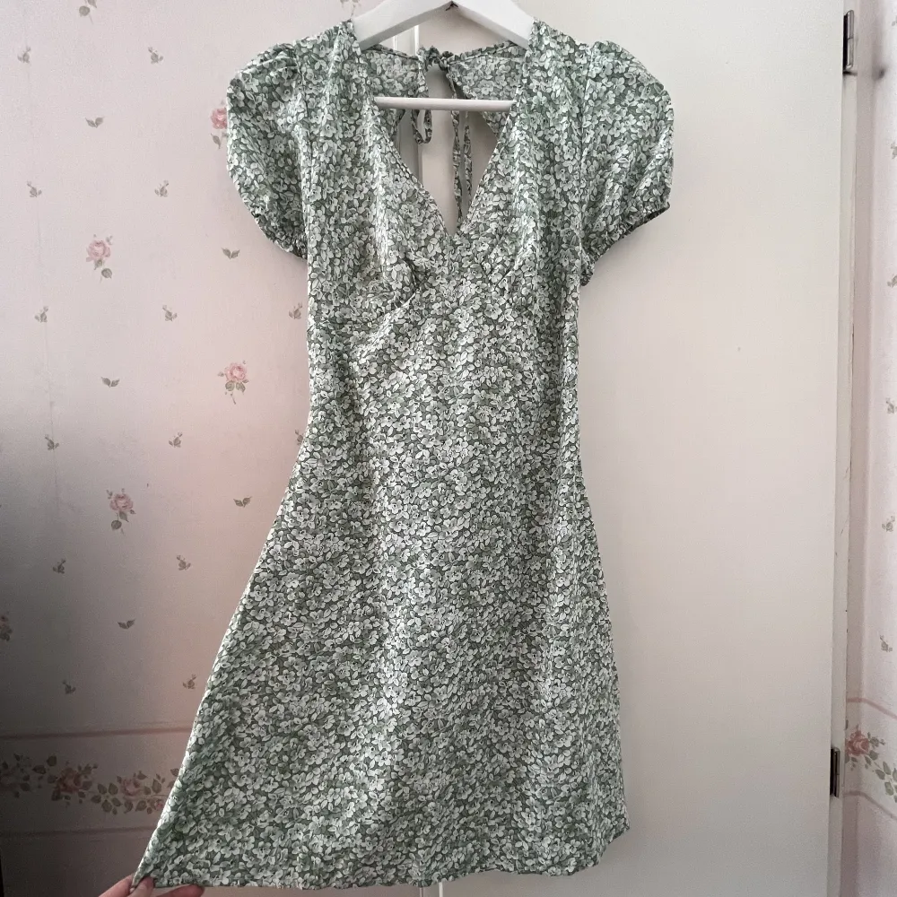 En grön blommig klänning med öppen rygg och knyte bak🥰 Dragkedja som syns på bilden, storlek XS från Shein. Aldrig använd, nyskick. Skriv för mer bilder🥰. Klänningar.