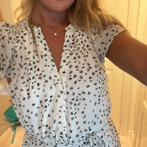 Klänning  - Kortärmad skjortklänning med knappar längst hela vägen samt band för justerbar midja storlek S