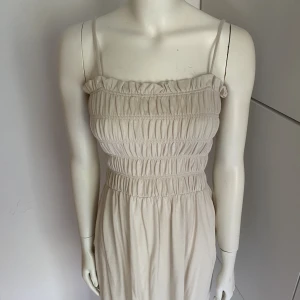 Lång vit klänning - Superfin lång vit/beige klänning från H&M i storlek XS. Superskönt material med 100% bomull. Använd 1 max 2 gånger. Superfint skick. Perfekt för sensommaren och tidig höst med en kofta 🤍👗