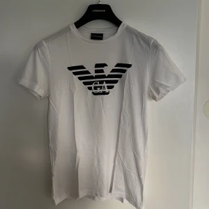 Emporio Armani t-shirt - Vit Emporio Armani T-shirt i storlek M, funkar för strl S. Skicket är fint utan defekter. Som vanligt nås jag på dm för frågor mm.