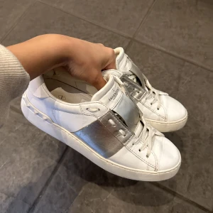 Valentino Garavani Rockstud sneakers silver - Låda, dustbag och extra oanvända snören tillkommer! Tar alltid hand om mina saker så likt dessa sneakers så är de i väldigt bra skick. (obs! Höger sko har blivit lagad i hälen pga slitning från en knöl. Se bild 2.) Nypris: 6945kr 