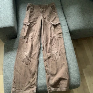 Bruna cargobyxor - Bruna vida cargobyxor från Divided. Använda men bra skick. Vita sömmar med fickor på benen.