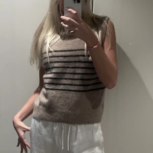Stickad väst - Säljer denna randiga väst från ARKET. Den är mörk beige med svarta ränder. Är aldrig använd så väldigt bra skick. 🤎