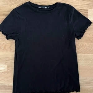 Svart ribbad t-shirt - En jättefin svart ribbad topp med lite volang på ärmarna💓Bara använd ett par gånger. Den är i strl S och är från lager 157. Kontakta mig för mer information 