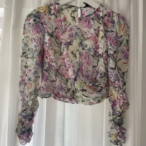 Blommig blus - Färgglad blus med scrunchade armar, från Lindex. Kortare modell, gömd dragkedja i sidan. Knappt använd.
