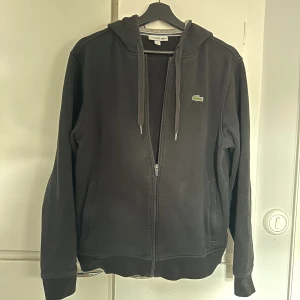 Lacoste zip - En zip från Lacoste i storlek M, sitter mer som en S. Inköpt för ca 1600kr. Finns ett brännhål i luvan som går att fixa enkelt om man orkar.