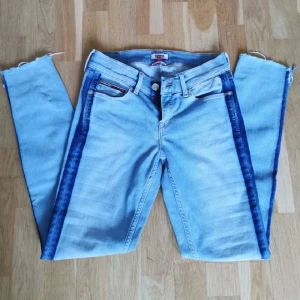 Blåa low/mid rise Tommy Hilfiger jeans - Supercoola blåa jeans från Tommy Hilfiger. Designen är så unik! De är inte avklippta av mig, utan det är så de är designade. Perfekta till ! ☀️
