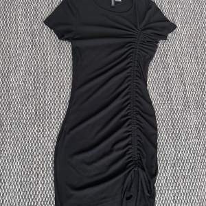 Jättefin svart tight dragsko klänning i väldigt bra skick från HM i strl XS! Säljer den för att den inte passar mig längre. 