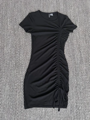 Svart dragskoklänning  - Jättefin svart tight dragsko klänning i väldigt bra skick från HM i strl XS! Säljer den för att den inte passar mig längre. 
