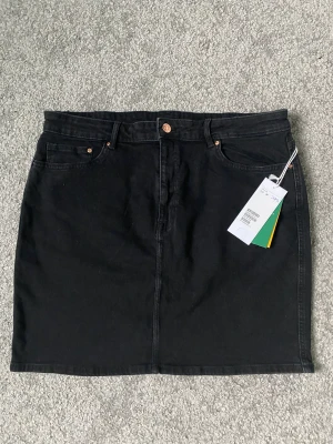 Svart kort jeanskjol - Helt ny, kort jeanskjol med prislappen kvar. Storlek 44 från HM. Nypris 299 kr.