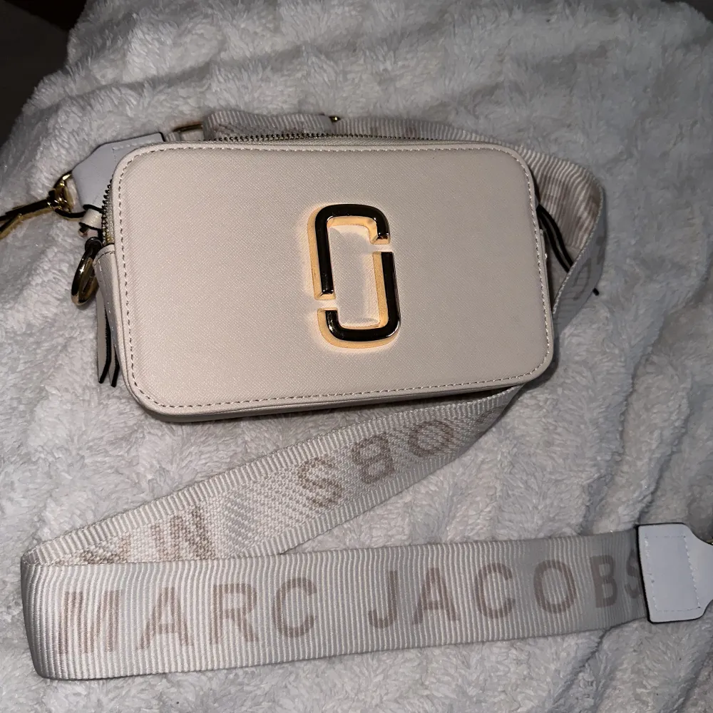 En helt ny och fräsch fake Marc Jacobs axelväska i beige/vit med guld detaljer. Den är oanvänd. Priset kan diskuteras!. Väskor.