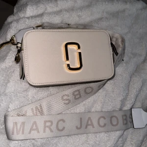 Marc Jacobs fake väska i beige/vit - En helt ny och fräsch fake Marc Jacobs axelväska i beige/vit med guld detaljer. Den är oanvänd. Priset kan diskuteras!
