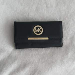 En svart plånbok MK.. Aldrig använd.  Kan tänka mig byta mot andra märkessaker. 