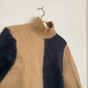 Stickad tröja - En stickad tröja uppdelat i marinblå & brun med ribbad polo krage från &OtherStories. Använd ca 2 gånger men tvättade i fel grader så den har blivit tajtare så numera storlek S/M. Köpt för 890kr säljer för 500kr. 