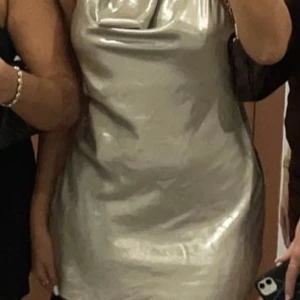 Superfin klänning från Zara - Säljer nu denna superfina klänning från Zara. Modellen på klänningen är öppen i ryggen med halterneck och knytning i nacken. Otroligt fin nästan metallic champange färg och sparsamt använd en gång.