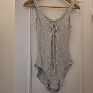 Body ljusgrå stl.36 - Fin mjuk body med band , snörning framtill. Ljusgrå.  Stl.36. H&M. Nya! Aldrig använt.