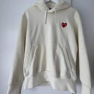 Ljusgul hoodie från comme des garcons i storlek S. Den är väl använd och har tecken på slitage samt fläckar på ärmarna. 