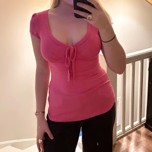 Rosa tröja - Rosa stretchig tröja. Knytning vid bysten och rynk vid axlarna.