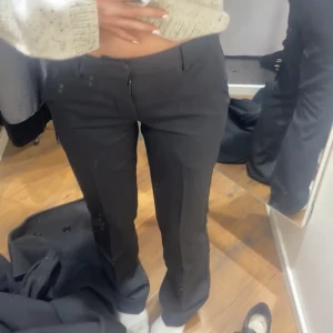 Lågmidjade kostymbyxor  - Svarta lågmidjade kostymbyxor med slits. 