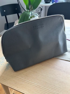 Rymlig necessär - Stor och rymlig, mörkgrå necessär från Kerstin Florian. Oanvänd.