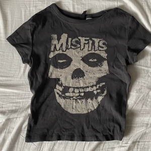 MisFits - En Misfits tshirt. Den har korta ärmar och är en magtröja. Den sitter också tight.