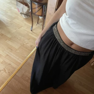 Snygg långkjol från zara som är oanvänd  - Väldigt snygg och trendig kjol från zara som dessvärre inte kommer till användning längre, i väldigt fint skick. Svart lång kjol i satin med små stenar på toppen