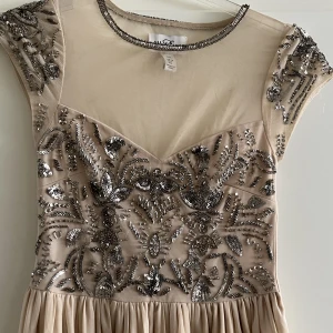 Festklänning  - Festklänning i nyskick, champagne färgad med silvriga paljetter. Maxiklänning. Storlek 34 från Nelly. Endast använd 1 gång. Priset kan diskuteras vid snabb affär. 