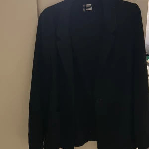 Kavaj  - Svart kavaj med fickor från H&M i storlek 34. Säljes för att den inte kommer till användning, inga defekter. 